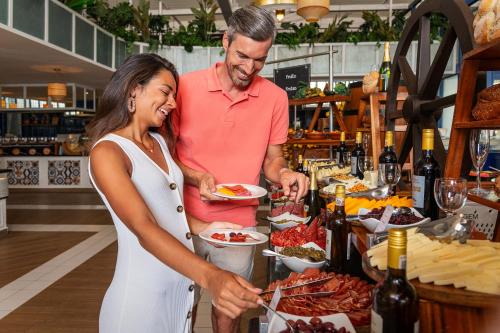 a man and a woman preparing food at a buffet at Ocean Riviera Paradise All Inclusive in Playa del Carmen