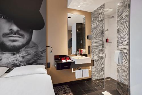 a bathroom with a bed and a sink and a mirror at LÉGÈRE HOTEL Tuttlingen in Tuttlingen