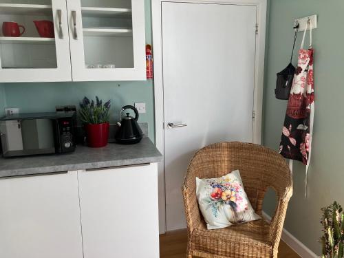 a kitchen with a wicker chair with a pillow on it at Cosy 1 bed apartment near Crantock beach in Crantock