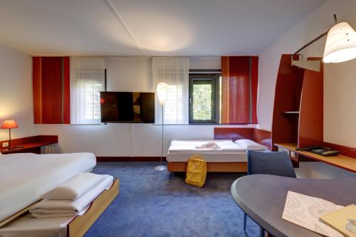 a hotel room with two beds and a table at Novotel Suites München Parkstadt Schwabing in Munich