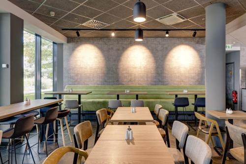 a restaurant with wooden tables and chairs and windows at Novotel Suites München Parkstadt Schwabing in Munich
