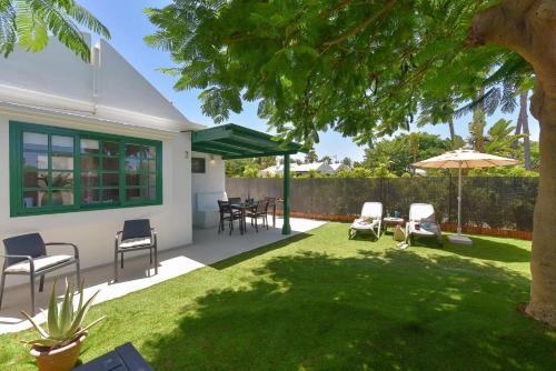 a backyard with a table and chairs and an umbrella at Cozy Bungalow Playa Flor Maspalomas by VillaGranCanaria in Maspalomas