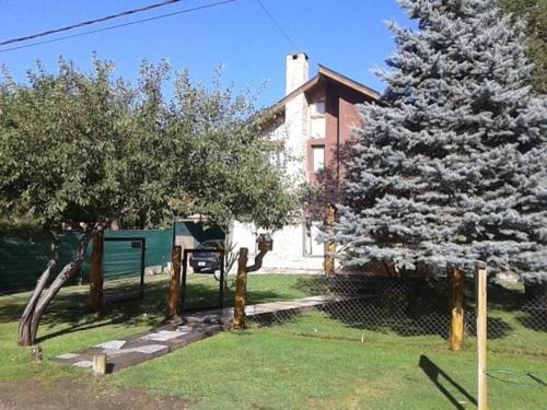 a christmas tree in front of a house with a fence at Cabañas Orillas del Chimehuín -Cabaña Chica 4 pax- in Junín de los Andes