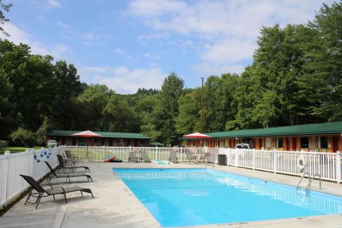 a swimming pool with chairs and a building at Two Rivers Lodge in Bryson City