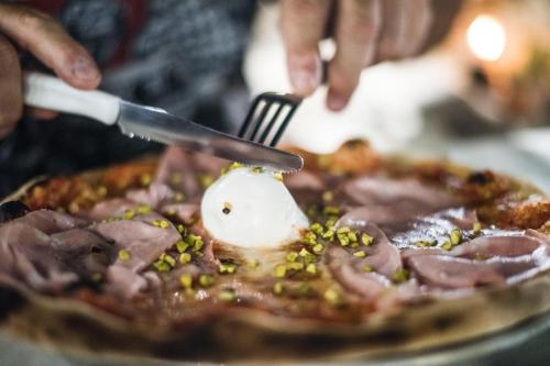 a person cutting into a pizza with a knife and fork at B&B Casa Cosmano in Brancaleone Marina