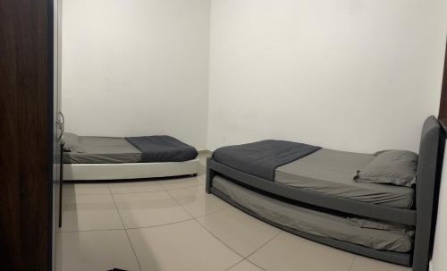 two beds sitting in a room with a mirror at Sungai Udang Homestay 4 bilik in Melaka