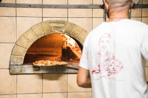 a man standing in front of a pizza oven at B&B Casa Cosmano in Brancaleone Marina