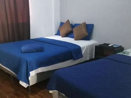 two beds in a room with blue sheets and pillows at costa azul apartment el zonte in La Libertad