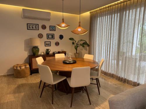 a dining room with a wooden table and white chairs at Departamento en Puerto Aventuras in Puerto Aventuras