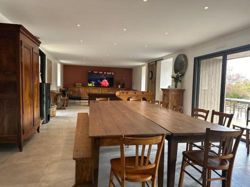 une salle à manger avec une grande table et des chaises en bois dans l'établissement Entre St Malo et Rennes, grande maison 12 couchages Chez Yvonne, à Irodouër