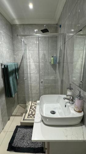 a bathroom with a white sink and a shower at The Manor in Midrand