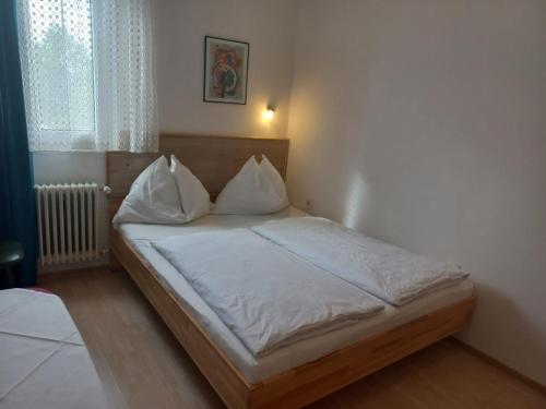 滨湖魏登Hotel Weidnerhof的卧室里有一张床，床单和枕头都是白色的