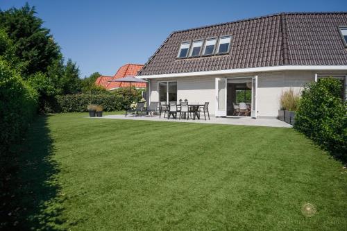 una casa con un patio con césped verde en Vakantiehuis Noordwijk, en Noordwijk