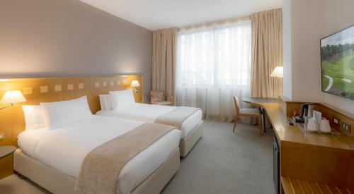 a hotel room with two beds and a desk at Carlemany Girona in Girona