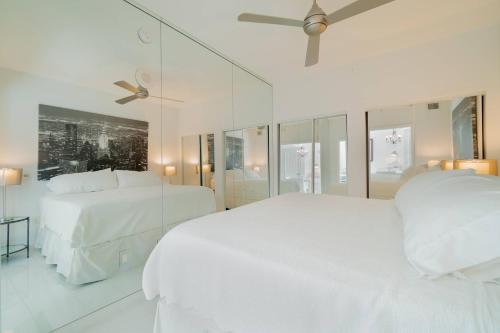 a white bedroom with two beds and a ceiling fan at The Palms Suite - Casa Costa 309S 1 Bedroom, Pools, Jacuzzi, Beach, Shops & Dog Friendly in Boynton Beach