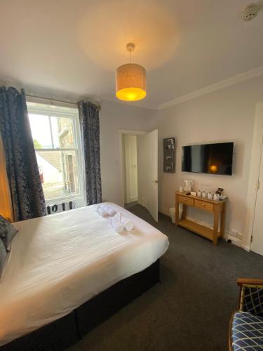 a bedroom with a large white bed and a television at Craigvrack Hotel & Restaurant in Pitlochry