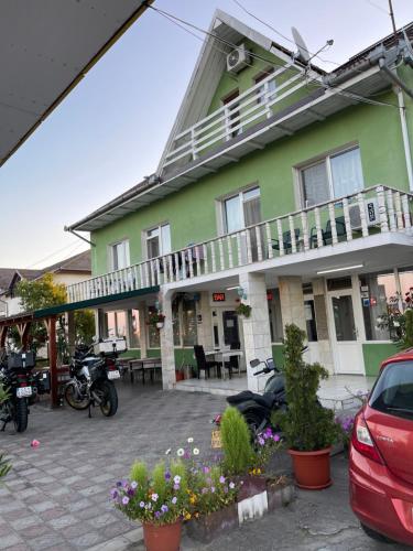 a green building with motorcycles parked in a parking lot at Pensiunea Simina in Caransebeş