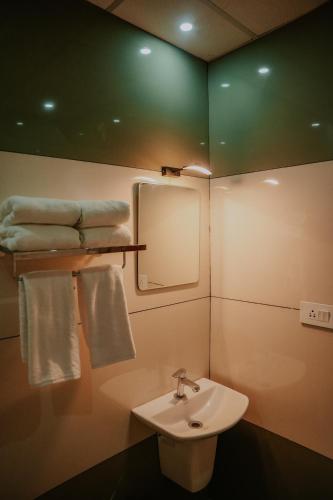a bathroom with a sink and a mirror and towels at Makkiyil Residency in Ernakulam