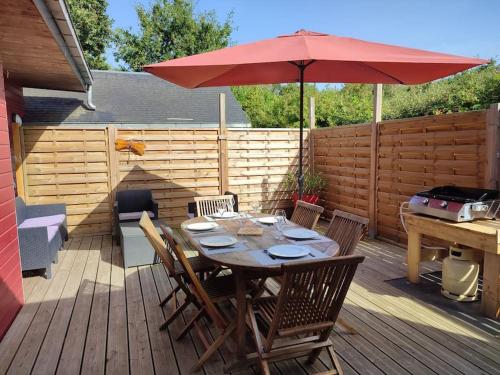 une terrasse en bois avec une table et un parasol rouge dans l'établissement Chez Gwen et Lulu - Maison en Bois - Trébeurden, à Trébeurden