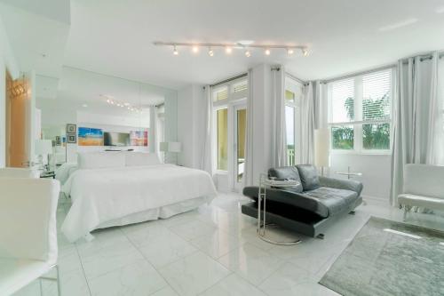 a large white bedroom with a bed and a chair at The Beachy Blues Suite - Casa Costa 308S Studio, Pools, Jacuzzi, Beach, Shops & Dog Friendly in Boynton Beach