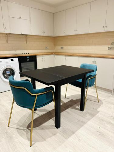 a black table and two blue chairs in a kitchen at Victoria Studios in London