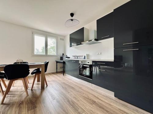 une cuisine avec une table en bois et des armoires noires dans l'établissement Le Coquet-T3-Wifi-parking, à Rouen