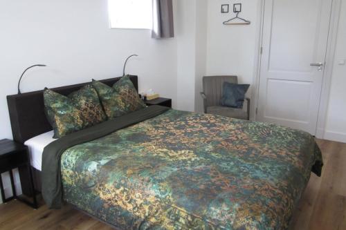 a bedroom with a large bed and a chair at Aan de Dijk in Edam
