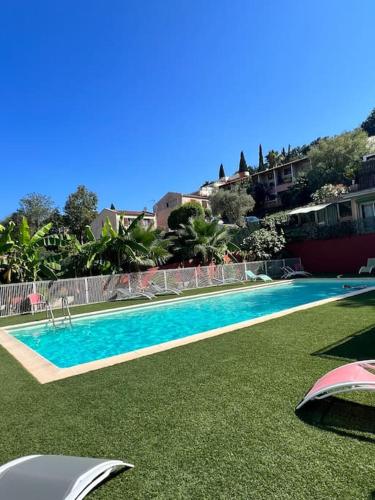 - une piscine avec de l'herbe verte à côté d'un bâtiment dans l'établissement Appartement dans résidence avec piscine, à Villeneuve-Loubet