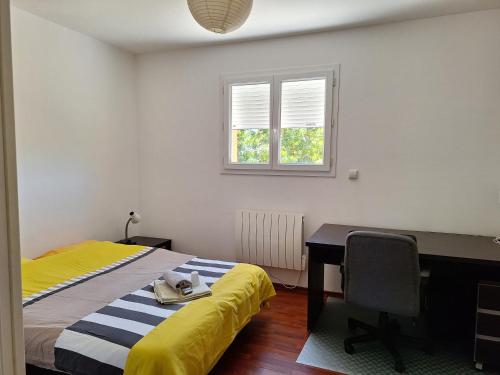 a bedroom with a bed and a desk and a window at Maison tout confort Figeac in Figeac
