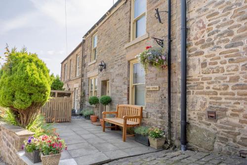a patio with a bench in front of a brick building at Danes Cottage - Luxury Peak District Retreat in Chapel en le Frith