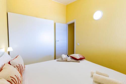 a bedroom with a large white bed with yellow walls at Incantevole Vista Mare, 450mt Spiaggia Kal'e Moru in Geremèas