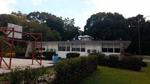 a white house with a red sculpture in front of it at Hotel Los Leones in Palenque