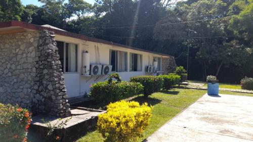 a house with a stone wall and flowers in the yard at Hotel Los Leones in Palenque