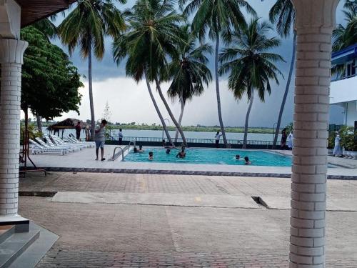 a pool with palm trees and people in the water at Treatooo Lake resort in Batticaloa