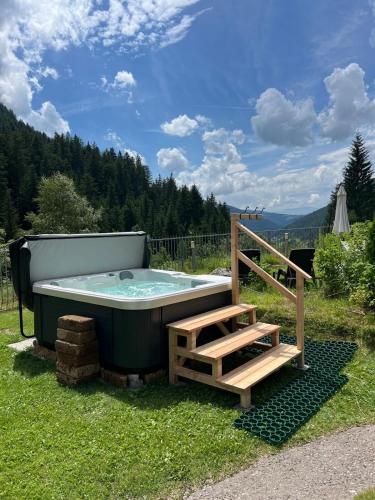a hot tub in the grass with a wooden staircase at Hotel Rosengarten in Nova Levante