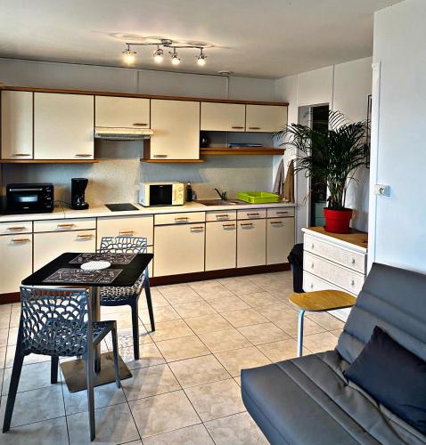 une cuisine avec des armoires blanches et une table et des chaises dans l'établissement écho des vagues , vue mer, à Langrune-sur-Mer