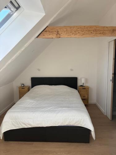 une chambre avec un grand lit blanc dans un grenier dans l'établissement Résidence des Voyageurs T2, à Plouharnel