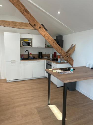 une cuisine avec des armoires blanches et une table en bois dans l'établissement Résidence des Voyageurs T2, à Plouharnel