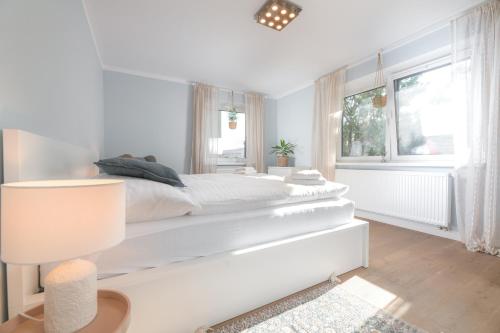 a white bedroom with a large bed and a window at Blue City apartments in Trenčín