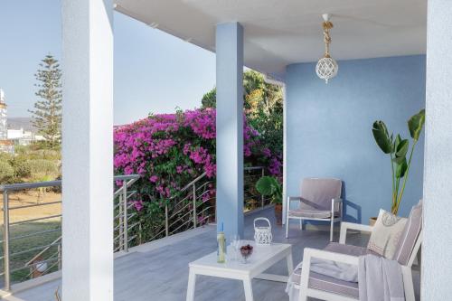 a balcony with purple flowers and a table and chairs at Villino Blu by the sea in Gouves