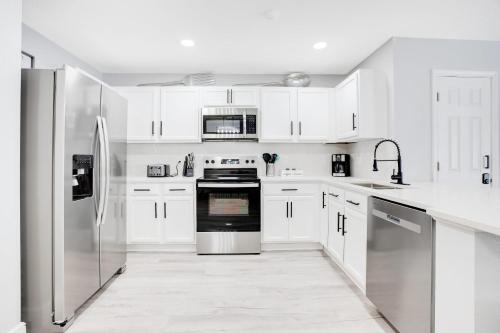 a kitchen with white cabinets and stainless steel appliances at Stylish Villa Near Disney & Universal in Kissimmee