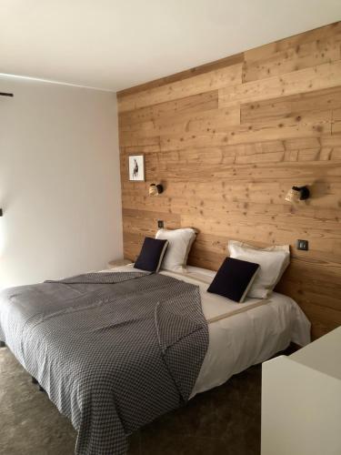a bedroom with two beds and a wooden wall at Le chalet Paula in Agos-Vidalos