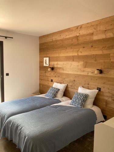two beds in a bedroom with a wooden wall at Le chalet Paula in Agos-Vidalos