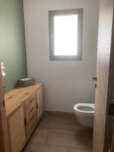 a bathroom with a toilet and a window at Le chalet Paula in Agos-Vidalos