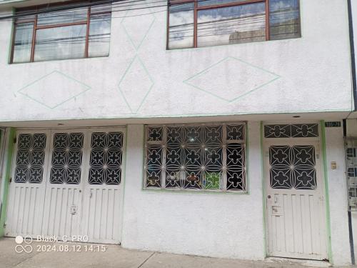a white building with two white doors and windows at Sweet Bed in Bogotá