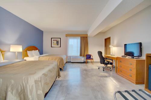 a hotel room with two beds and a desk and a tv at Quality Inn & Suites CVG Airport in Erlanger