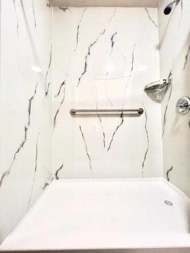 a bathroom with white marble walls and a shower stall at ECONOMY INN AND SUITES in Tulsa