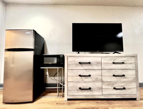 a television on top of a dresser with a refrigerator at ECONOMY INN AND SUITES in Tulsa