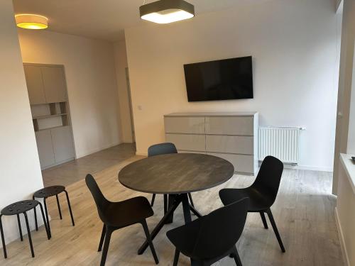 a room with a table and chairs and a flat screen tv at Apartamenty Osmolice w Stawach in Dęblin