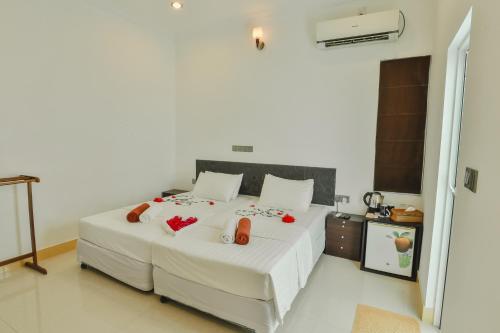 a bedroom with a large white bed with red flowers on it at Karanka Villa @ Mahibadhoo in Mahibadhoo